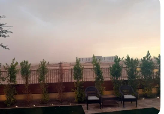 A haboob dust wall spanning the horizon behind a Valley backyard fence, the sky brown with approaching dust